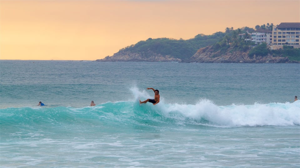 Puerto Escondido que incluye olas, un atardecer y vistas de una costa