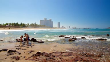 Mazatlan featuring rugged coastline and a sandy beach as well as a family