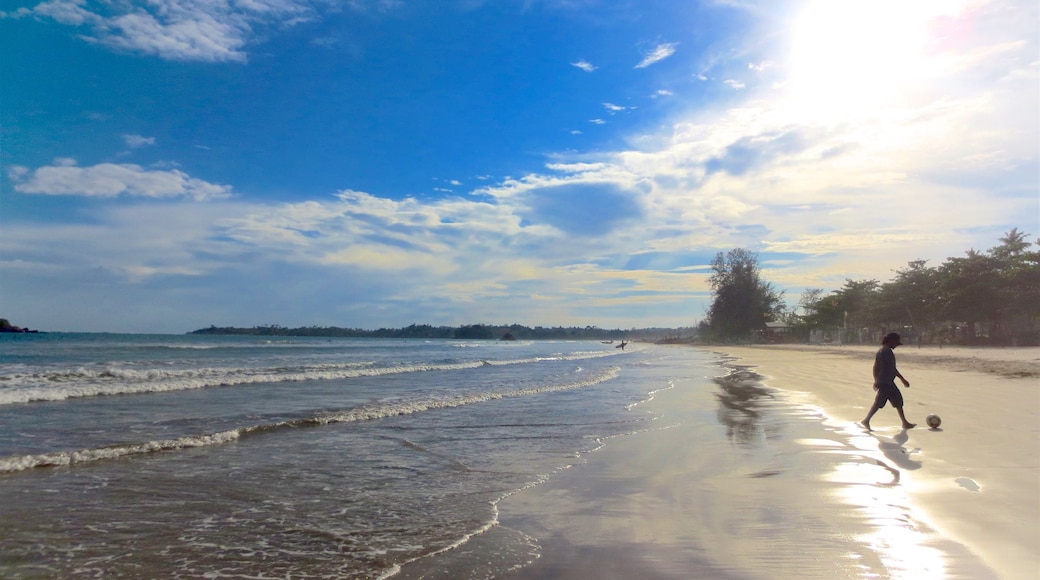 Weligama featuring surf and a sandy beach as well as an individual male