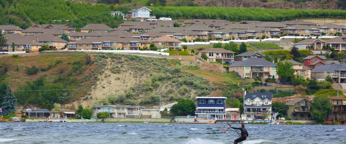Okanagan Beach johon kuuluu leijalautailu, pieni kaupunki tai kylä ja yleiset rantanäkymät