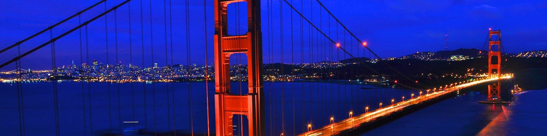 Golden Gate Bridge illuminated at night with city lights in the background in California, USA