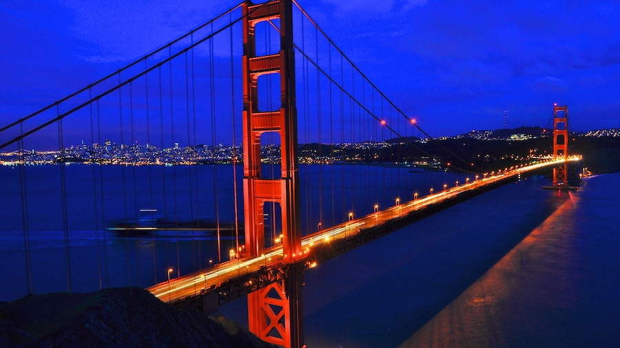 Golden Gate Bridge illuminated at night with city lights in the background in California, USA