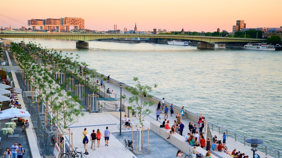 Colonia que incluye un atardecer, un río o arroyo y un puente