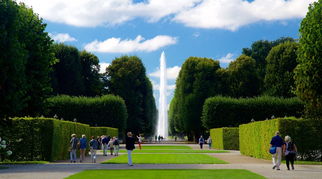 Herrenhausen Gardens showing a fountain and a park as well as a small group of people