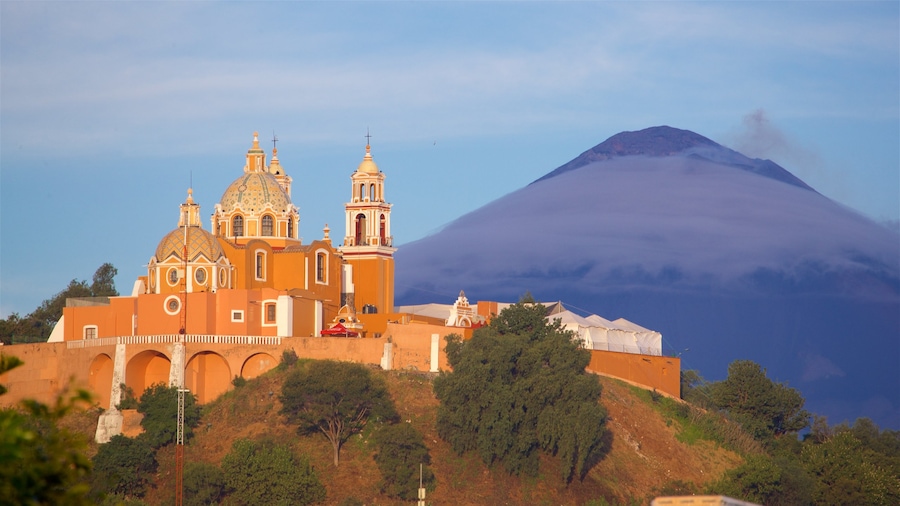 Santuario de La Virgen de los Remedios ofreciendo elementos patrimoniales, montañas y un atardecer