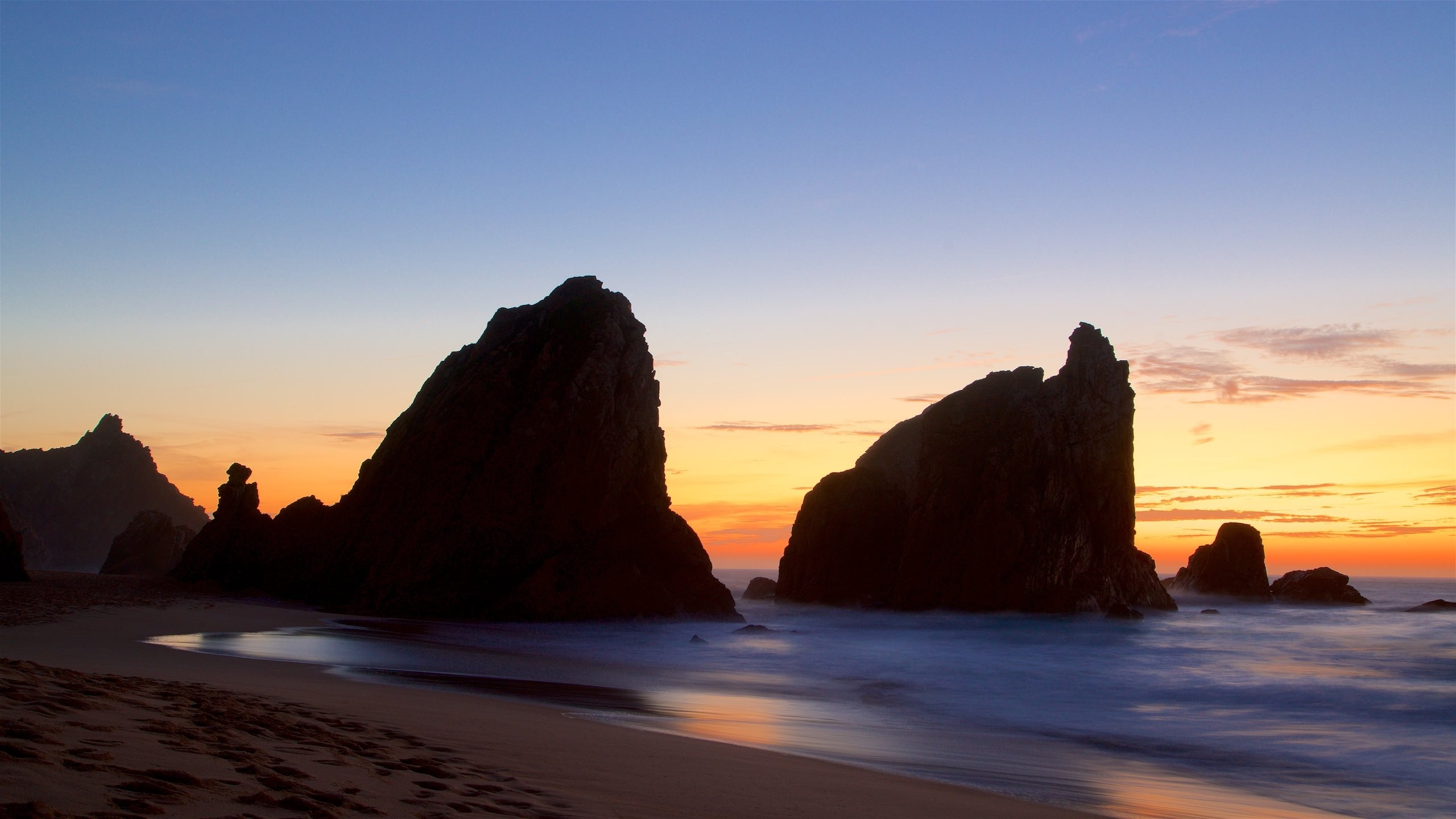 Ursa Beach which includes waves, a sunset and rocky coastline