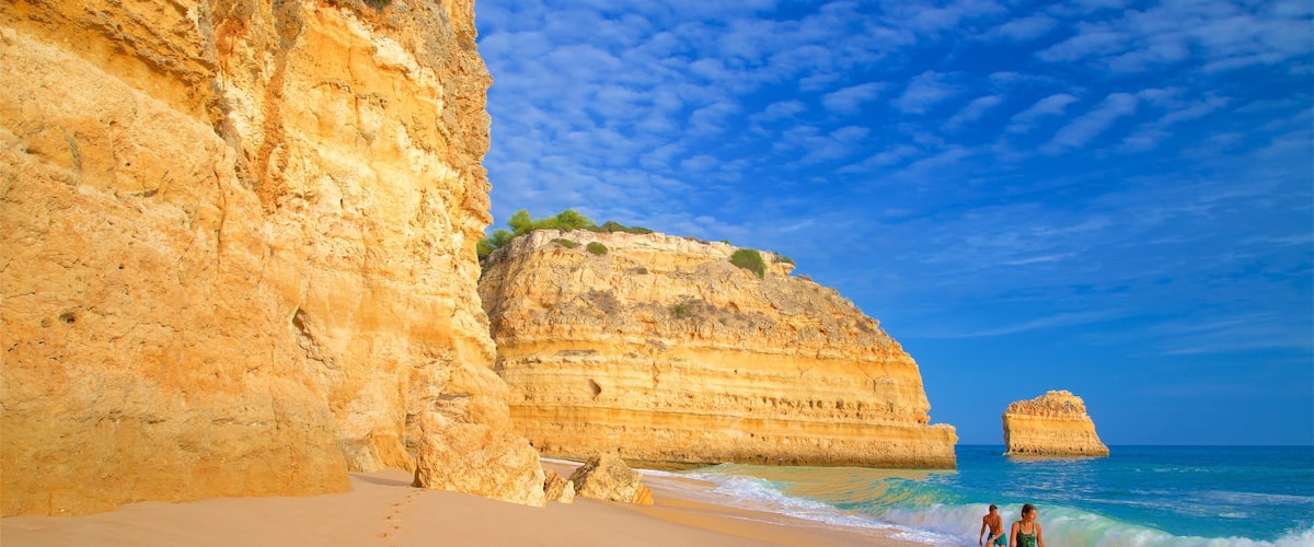 Playa Marinha mostrando olas, una playa de arena y litoral rocoso