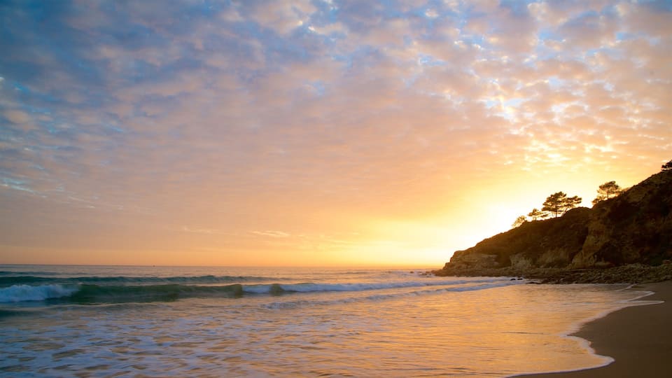 Strand Falesia inclusief ruige kustlijn, een zandstrand en een zonsondergang