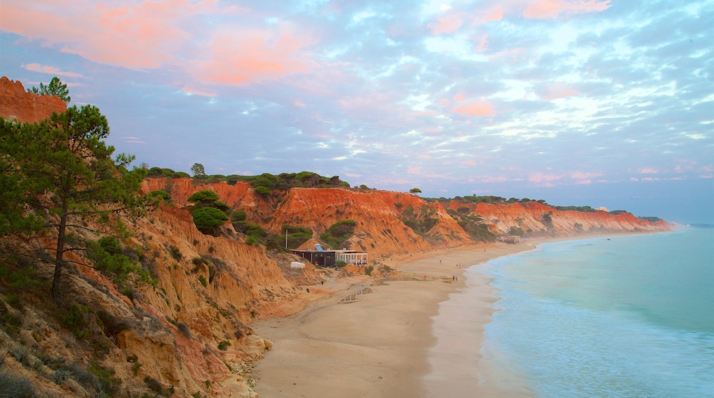 Falesia Beach which includes a sandy beach, a sunset and rocky coastline