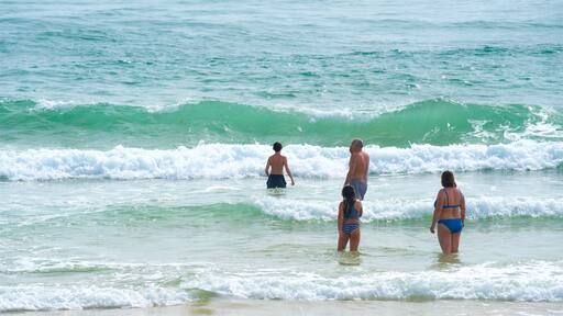 Fuzeta Beach som visar kustutsikter och surfing såväl som en familj