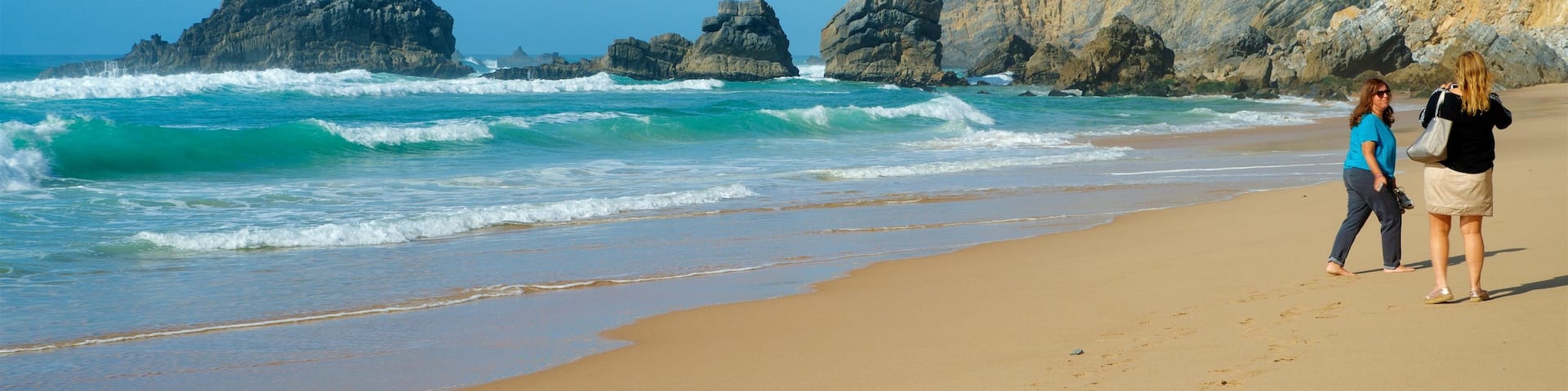 Adraga Beach featuring a beach, waves and rugged coastline