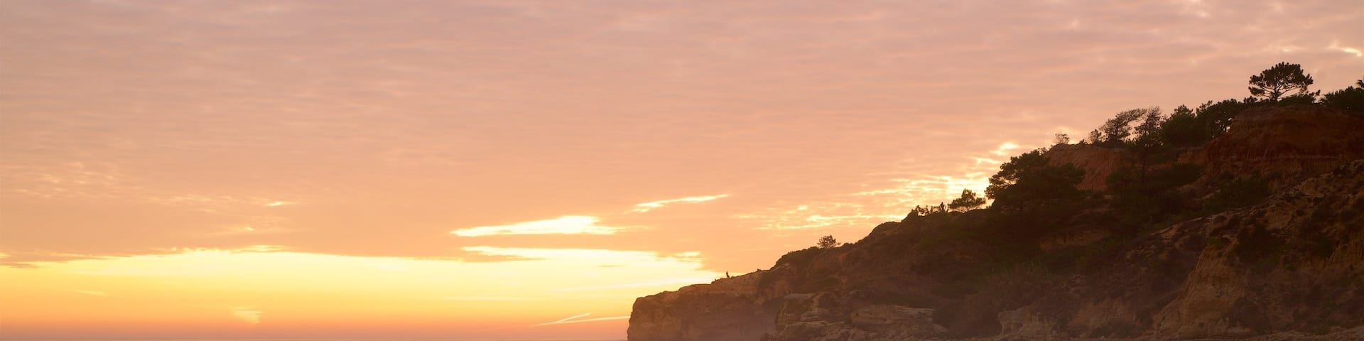 Falesia Beach featuring rugged coastline, general coastal views and a sunset