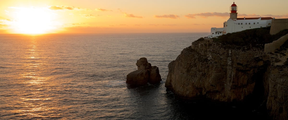 Cape St. Vincent Lighthouse which includes a sunset, a lighthouse and rugged coastline