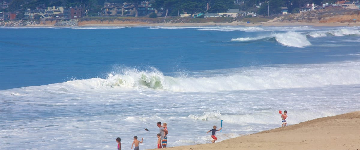 Half Moon Bay featuring yleiset rantanäkymät ja hiekkaranta sekä pieni ryhmä ihmisiä