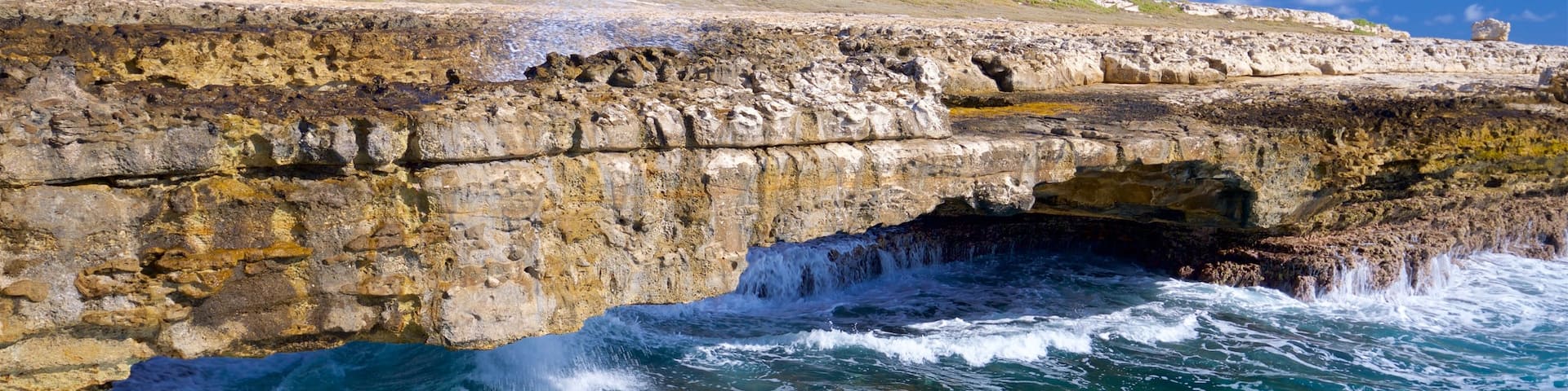 Devil\'s Bridge which includes rocky coastline, waves and general coastal views