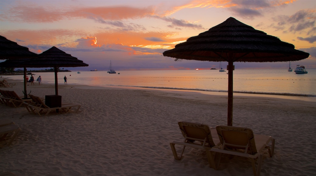 Dickenson Bay Beach ofreciendo una playa, un atardecer y vistas de una costa