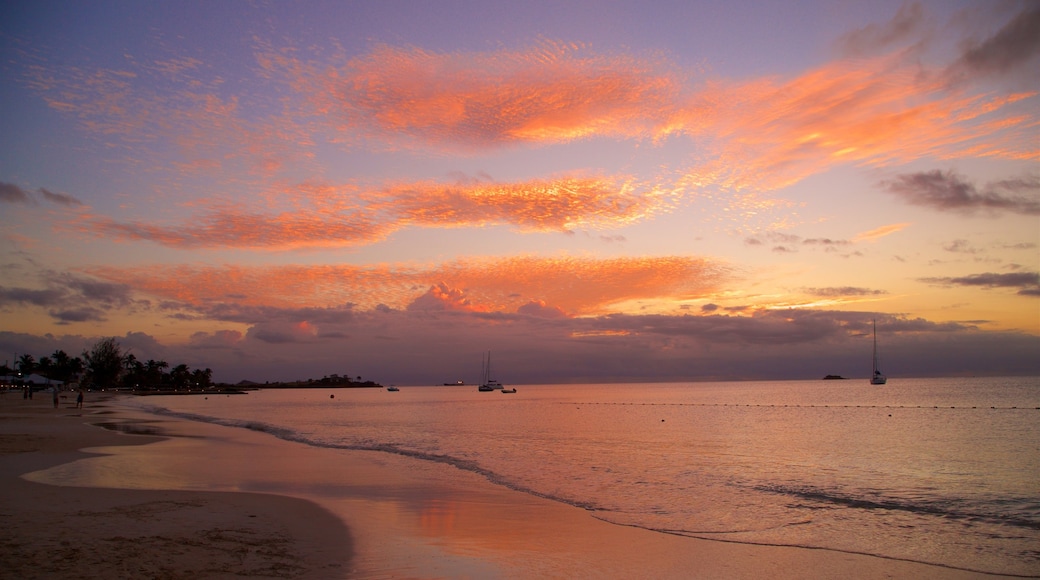 Dickenson Bay Beach que incluye una playa de arena, vista general a la costa y un atardecer