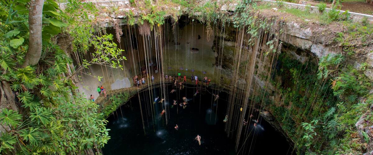 Cenote Ik kil que incluye natación y un lago o abrevadero y también un pequeño grupo de personas
