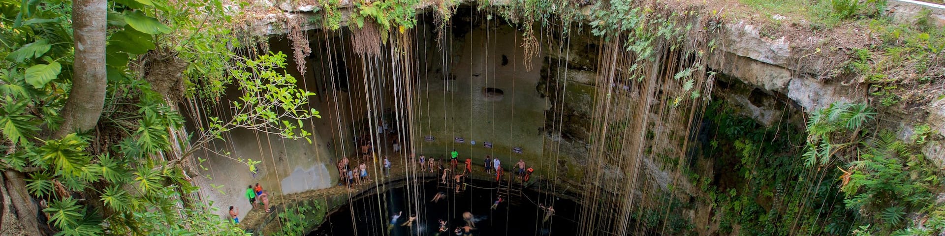 Cenote Ik kil featuring a lake or waterhole and swimming as well as a small group of people