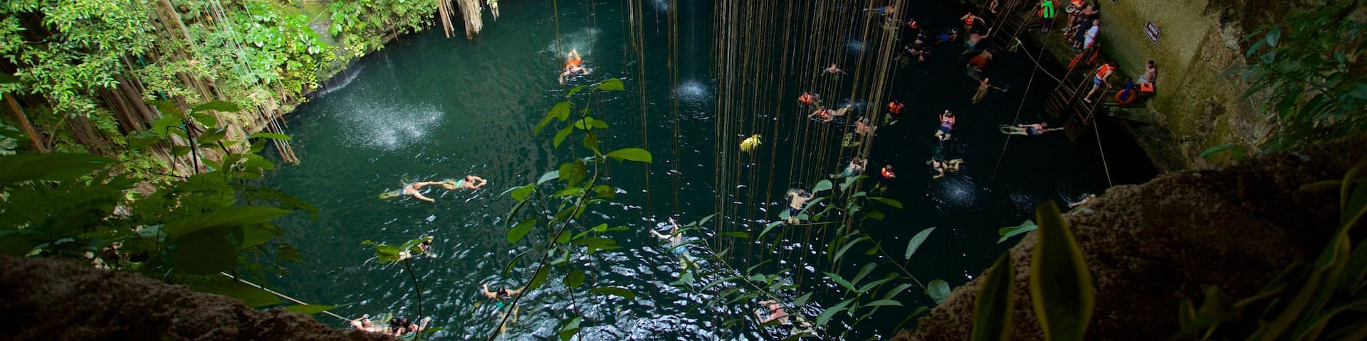 Cenote Ik kil which includes a lake or waterhole and swimming as well as a small group of people