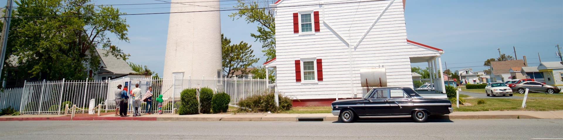 Fenwick Island Lighthouse showing a lighthouse and a house as well as a small group of people