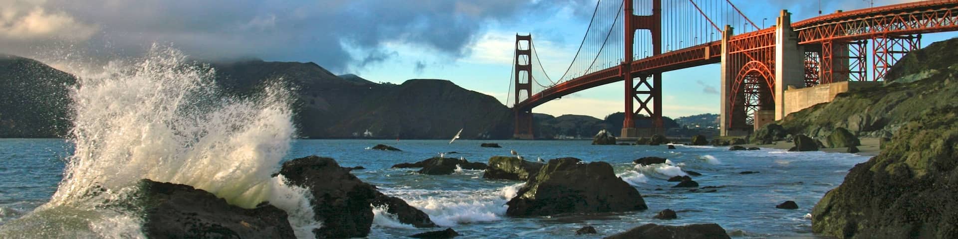 Baker Beach showing rocky coastline, landscape views and a bridge
