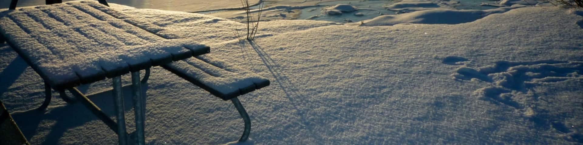 Helsinki winter landscape with frozen lake and sunlight casting shadows near Uusimaa, Finland