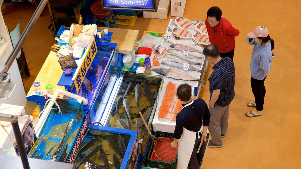 Mercado de Peixes Noryangjin mostrando comida e mercados assim como um pequeno grupo de pessoas