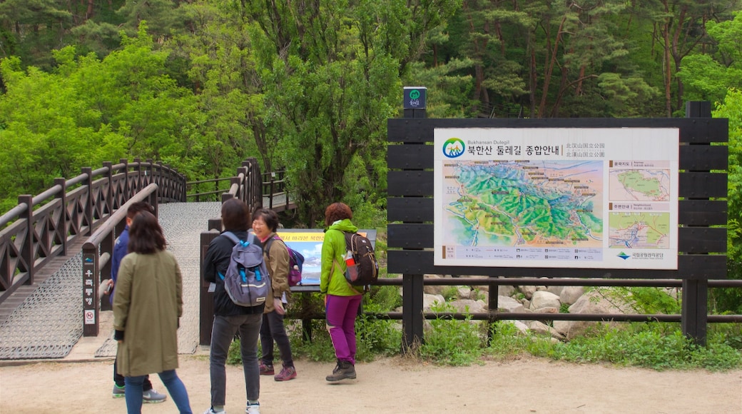 Bukhansan National Park featuring signage and forest scenes as well as a small group of people