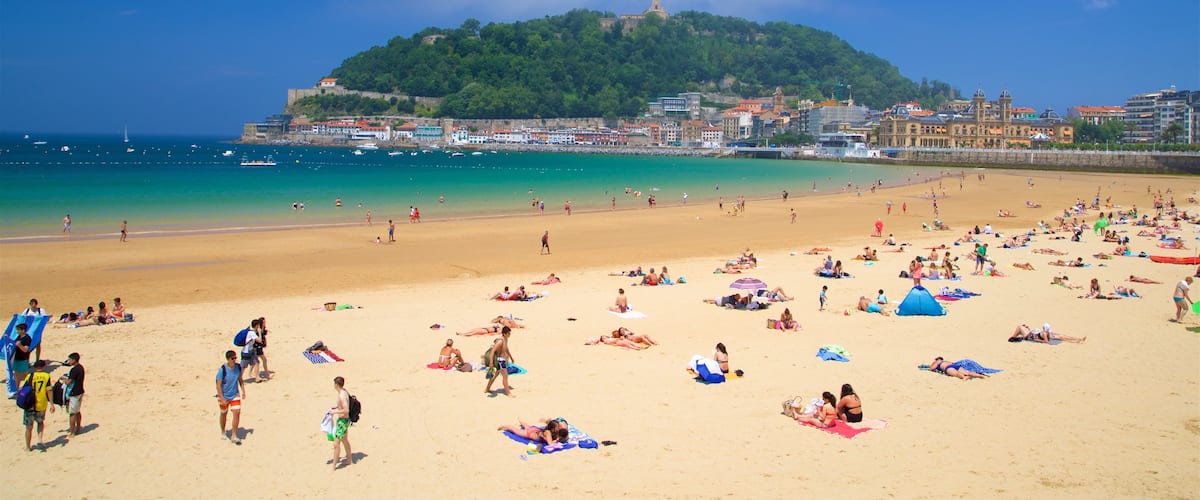 Concha Beach which includes a coastal town, a sandy beach and general coastal views