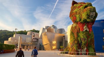 Guggenheim Museum Bilbao som visar modern arkitektur, utomhuskonst och en solnedgång