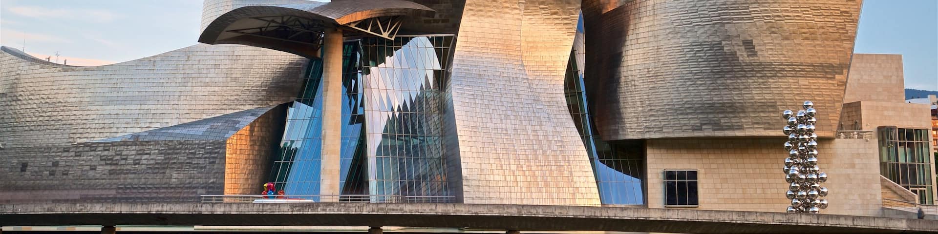 Guggenheim Museum Bilbao which includes modern architecture, a river or creek and a sunset
