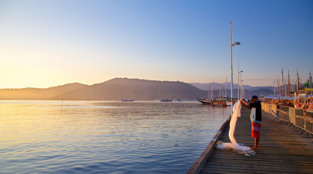 Paraty Wharf featuring a bay or harbour and a sunset as well as an individual male