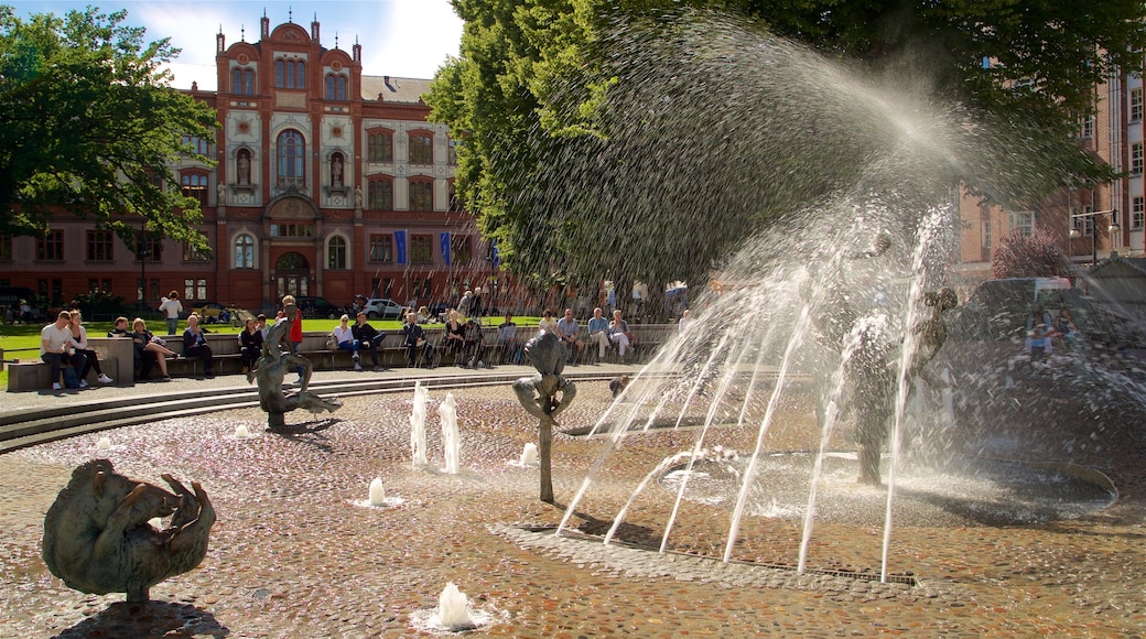 Universität Rostock mit einem Springbrunnen sowie kleine Menschengruppe