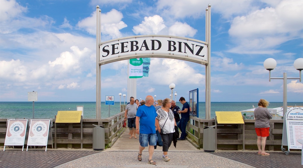 Seebrücke Binz welches beinhaltet allgemeine Küstenansicht und Beschilderung sowie kleine Menschengruppe