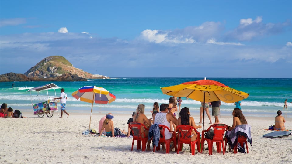 Arraial do Cabo que incluye vista general a la costa y una playa de arena y también un pequeño grupo de personas
