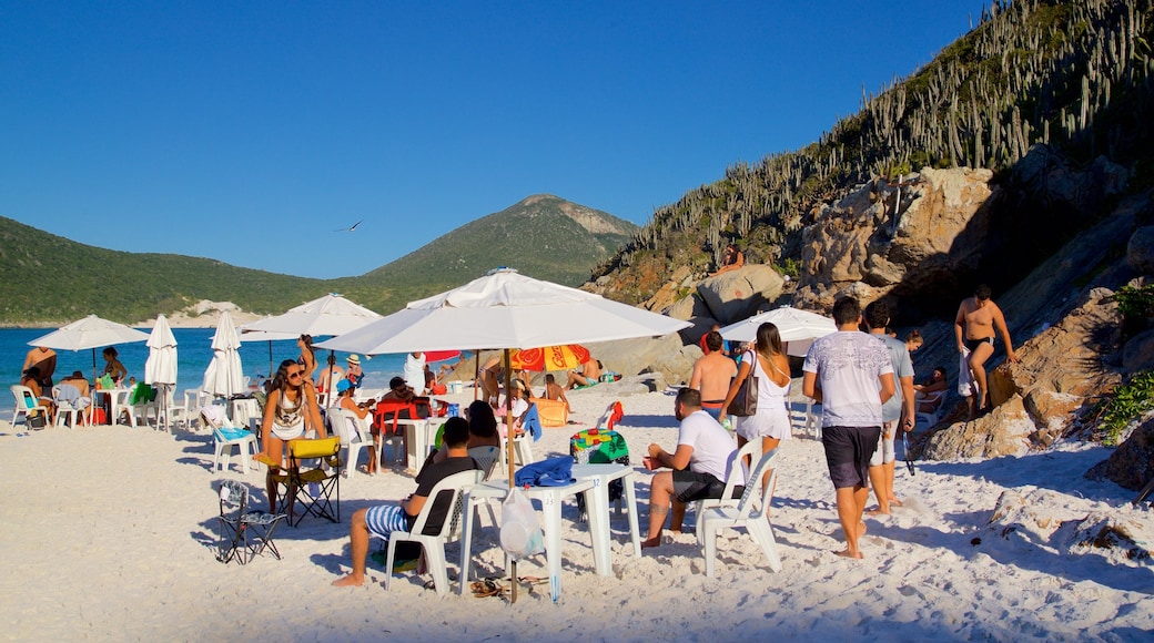 Pontal do Atalaia Beach which includes a sandy beach and general coastal views as well as a small group of people