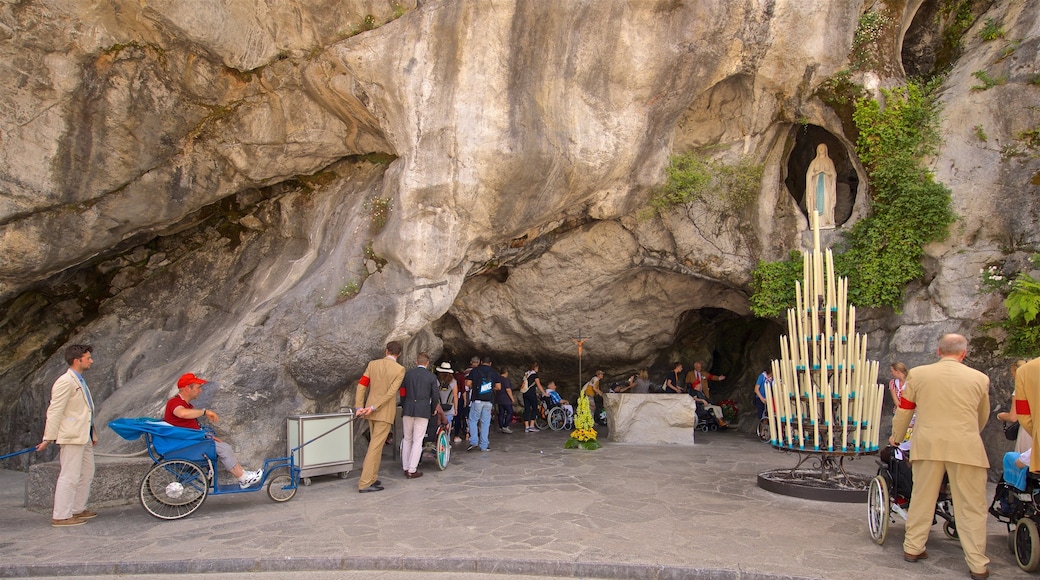 Grotte de Massabielle qui includes éléments religieux aussi bien que petit groupe de personnes