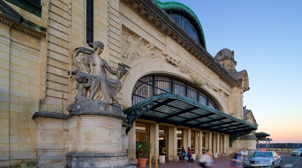 Gare de Limoges toont een zonsondergang, historische architectuur en een standbeeld of beeldhouwwerk