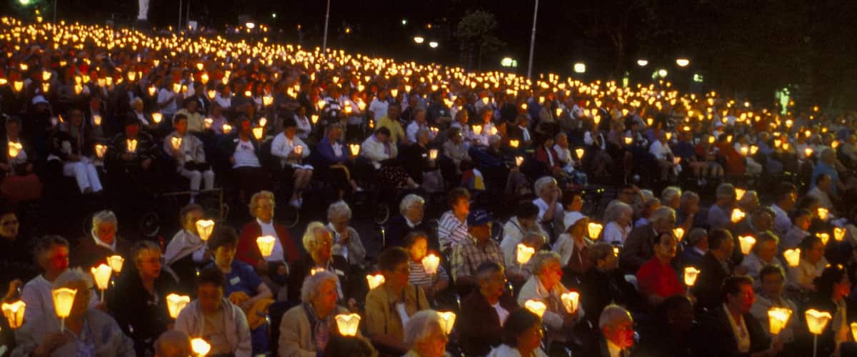 Lourdes showing night scenes and performance art as well as a large group of people