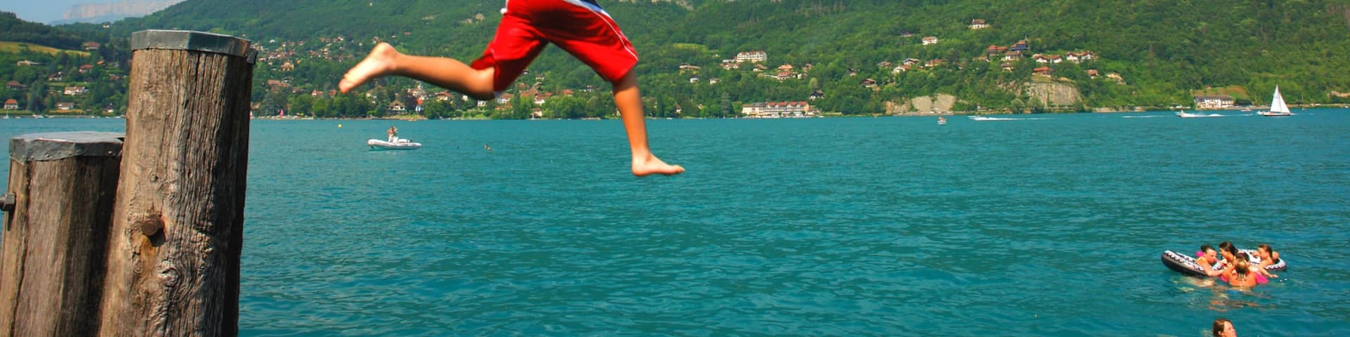 Lake Annecy featuring mountains and a lake or waterhole as well as an individual child