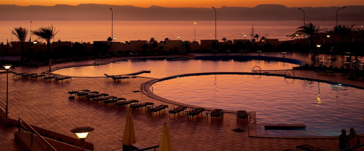 Aqaba which includes general coastal views, a sunset and a luxury hotel or resort