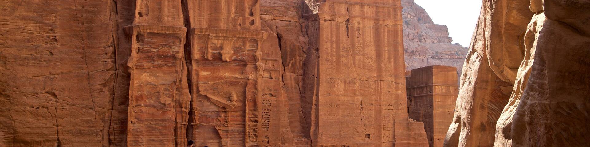 Street of Facades featuring a gorge or canyon and heritage elements as well as a small group of people