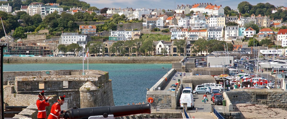 Castle Cornet mostrando artículos militares, elementos del patrimonio y una ciudad costera