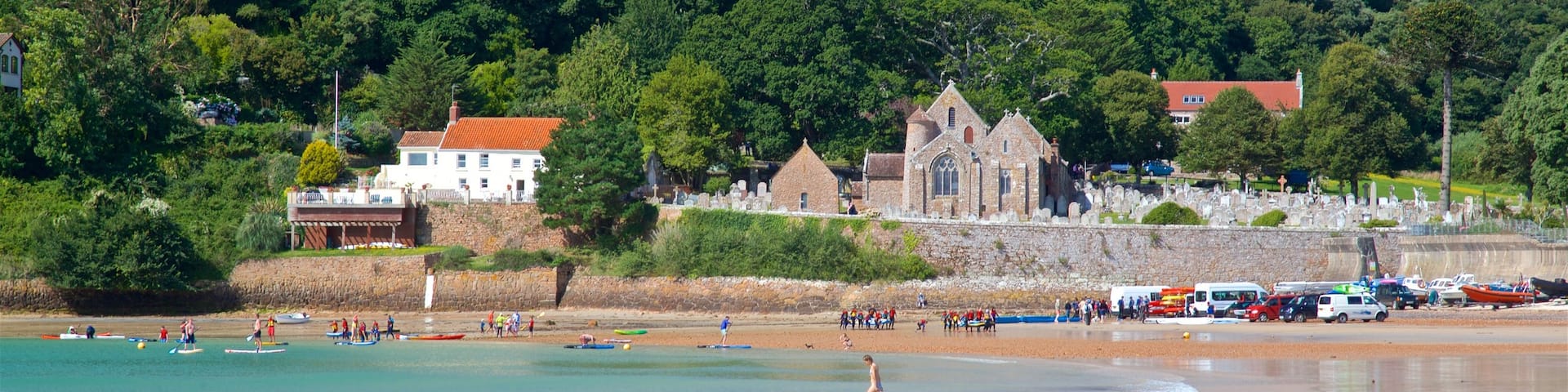 Parish Church of St. Brelade which includes a sandy beach, a coastal town and general coastal views