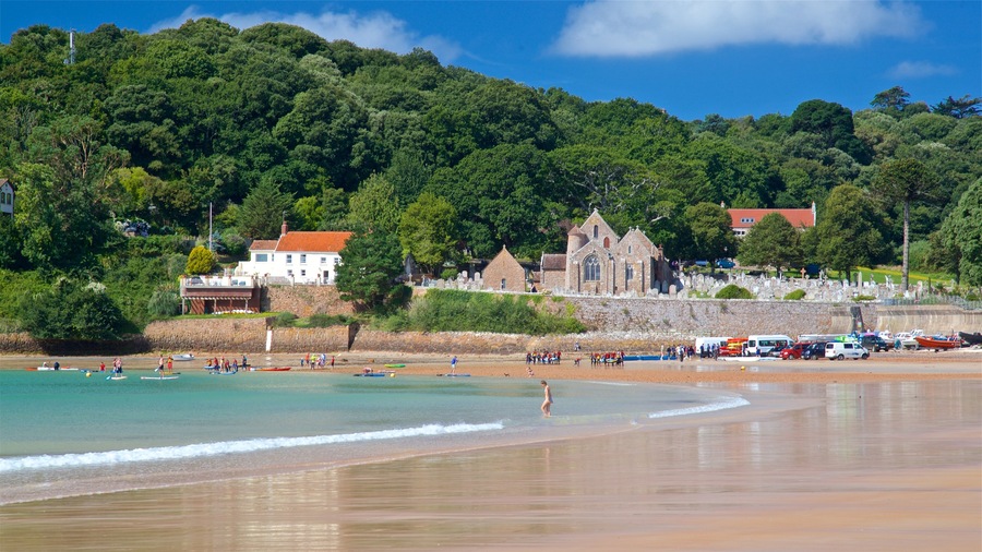 Parish Church of St. Brelade which includes a sandy beach, a coastal town and general coastal views