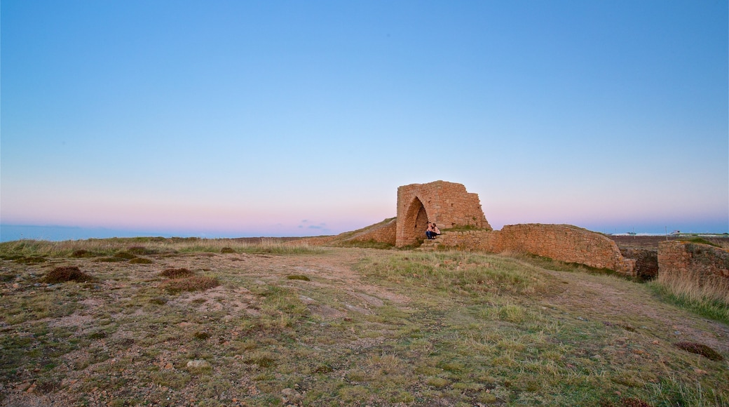 Grosnez Castle das einen Sonnenuntergang und Gebäuderuinen