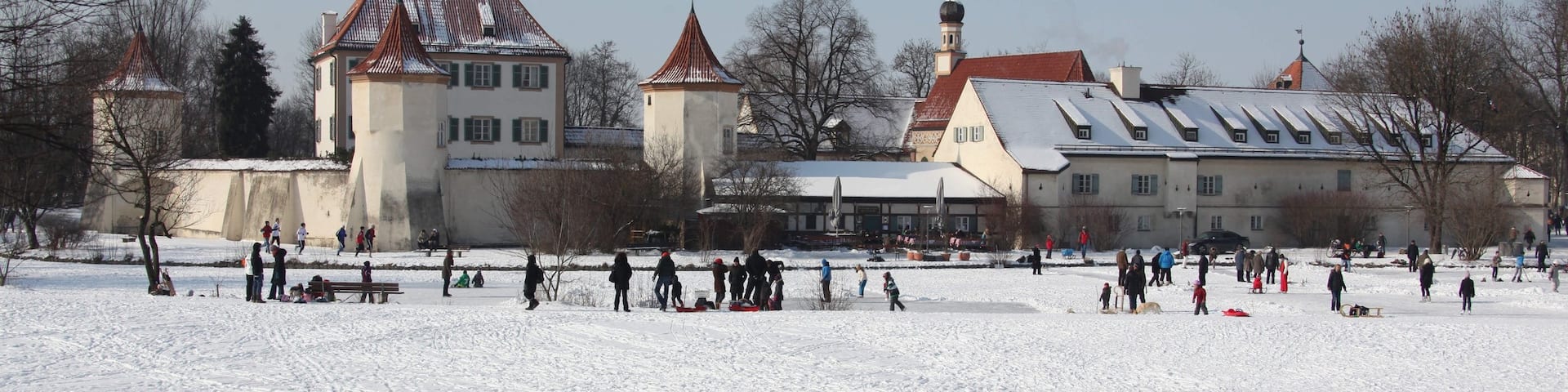 Blutenburg Castle showing snow and a small town or village as well as a small group of people