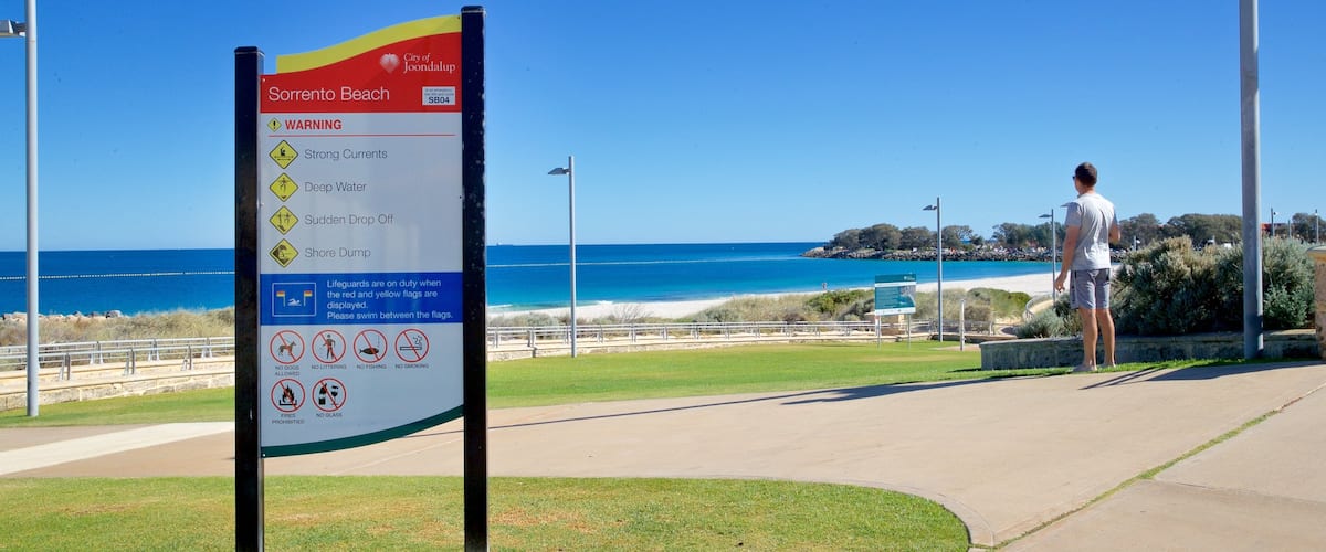 Sorrento Beach showing signage and general coastal views as well as an individual male