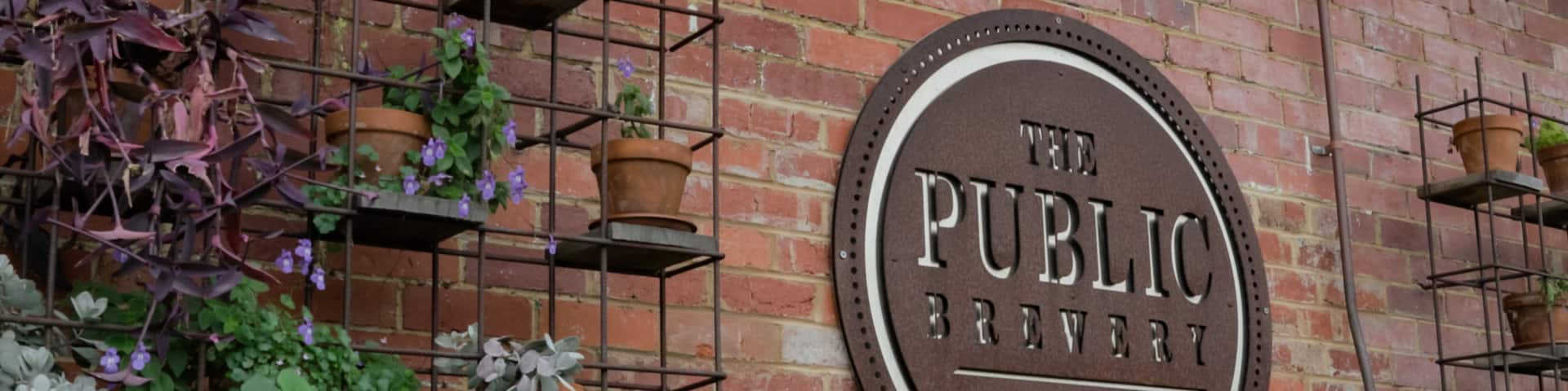 The Public Brewery featuring signage and flowers